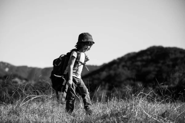 Sırt çantalı küçük bir çocuk manzaralı dağlarda yürüyüş yapıyor. Çocuk yerel bir turist yerel bir yürüyüşe çıkıyor. — Stok fotoğraf