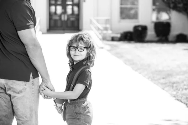 Portrait de l'élève heureux nerd tenant les enseignants par la main. Un écolier qui va à l'école avec son père. Parent avec enfant devant les portes de l'école. — Photo