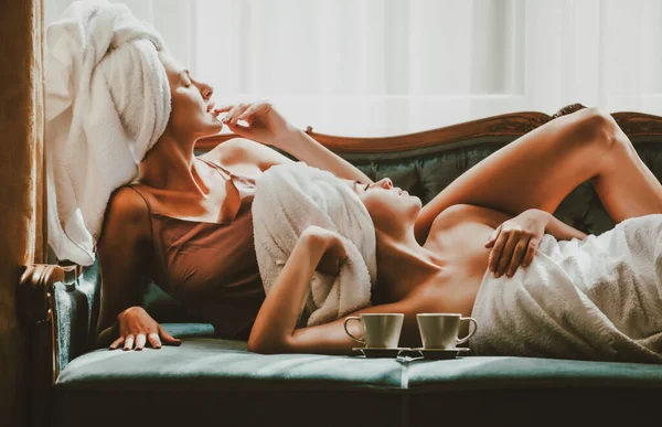Retrato de mujeres jóvenes divertidas en la cama en la habitación de hotel, divirtiéndose. Hermosas chicas sexy con albornoces y toallas. Preciosa ternura girlgriends. —  Fotos de Stock