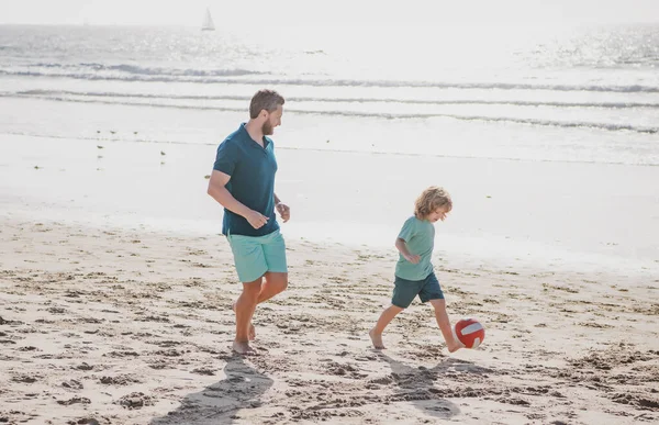 Pai e filho jogam futebol ou futebol na praia em férias em família de verão. Pai e criança brincando ao ar livre. — Fotografia de Stock