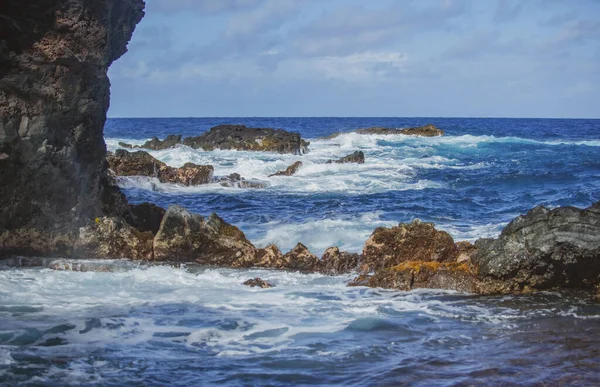 Mar azul e rochas a invadir. Spray de ondas sobre rochas. Costa do mar rochosa. — Fotografia de Stock