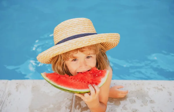 Un niño gracioso juega en la piscina. El niño come una sandía dulce, disfrutar del verano. Niñez despreocupada. — Foto de Stock