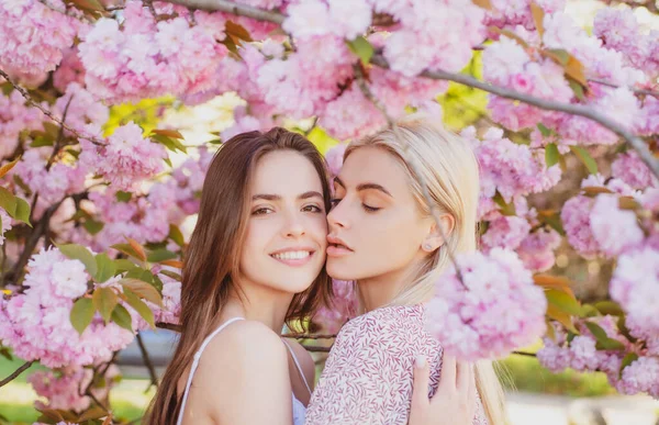 Raparigas da Primavera. Casal de lésbicas a beijar. bela primavera sexy jovem mulher com flores sakura. Beijo sensual. Lgbt.. — Fotografia de Stock