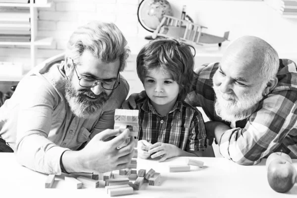 L'amitié des générations masculines. Grand-père enseigne à son petit-fils comment jouer à des jeux Jenga. Famille d'hommes. Trois hommes génération Jouer Jenga. — Photo