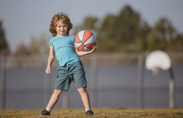 Chłopiec przygotowujący się do strzelaniny. Dzieciak pozowanie z piłką do koszykówki. — Zdjęcie stockowe