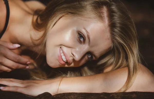 Młoda kobieta pozująca w studio na czarnym tle. Blondynka uśmiechnięta dziewczyna z bliska. Portret pięknej kobiety z ciemnym światłem na twarzy. — Zdjęcie stockowe