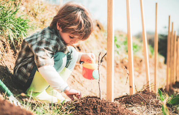Little farmer with Shovel and watering can. Little helper in garden Planting flowers. Child Farmer planting in the vegetable garden.