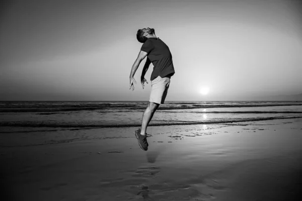 Mann springt am Strand, Silhouette im Sonnenuntergang. Wohlfühl- und Freiheitskonzept. — Stockfoto