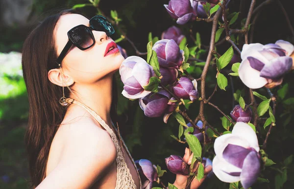 Vogue stile moda ritratto di giovane ragazza. Moda modello femminile con occhiali da sole all'aperto. Magnolia fiore sfondo . — Foto Stock