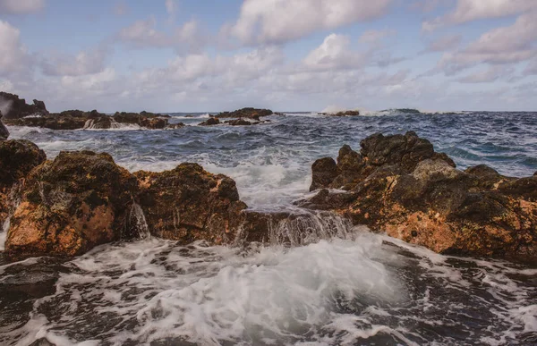 O mar colide com as pedras e areia de uma praia. ondas do mar linha de chicote impacto rocha. — Fotografia de Stock