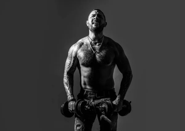 Portret van jonge atleet die oefeningen doet met halter in geïsoleerde donkere studio. Sportieve romp, man met halters. — Stockfoto
