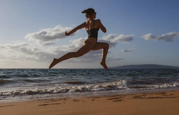 女は海岸を走る。ウォータープールで海の波に沿って走るアクティブなスポーティーな女の子は、フィット感と健康を維持します。女性のフィットネス、ジョギングワークアウト、夏休みのスポーツ活動. — ストック写真