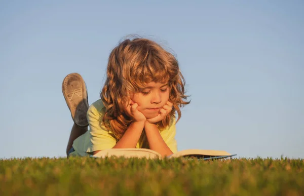 Niños aventura, libertad y niños despreocupados. Lindo niño leyendo libro fuera en la hierba. —  Fotos de Stock