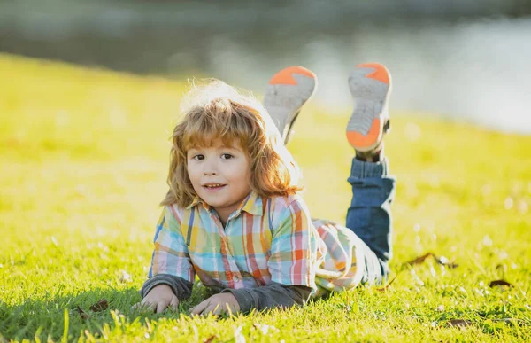 Child outdoor. Kid in park. Spring Boy lying on grass. Summer walk. Children adaptation. — Stock Photo, Image