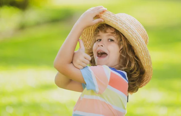 Retrato de uma criança rindo feliz no parque natural de verão com polegares para cima sinal. Miúdos positivos com chapéu de palha. Férias. — Fotografia de Stock