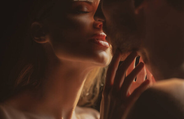Close up face of sensual portrait of a sexy couple embracing while dating. Young couple in love on black. The lovely coupl spends time together. Sensual couple in the tender passion.