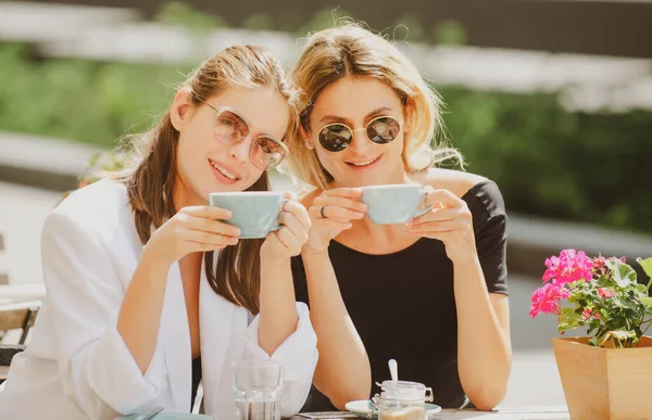 Romantic woman friends with coffee cup in cafe. Spending good time with best friend. Two beautiful women in sunglasses drinking coffee outdoors in vintage cafe. Attractive french women. — Fotografia de Stock