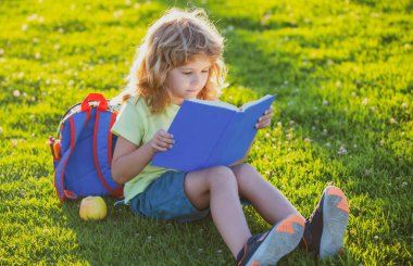 Çim arka planıyla ilgili güzel bir çocuk kitabı. Çocuklar parkta kitap okuyor. Öğrenme kavramı.