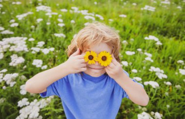Çocuklar bahar parkında eğleniyor. Yeşil çimenlikteki çocuk.
