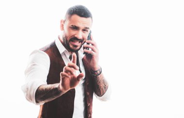 Telefondaki adam konuşuyor. Neşeli genç yakışıklı adam cep telefonuyla konuşuyor. Yakışıklı, heyecanlı, neşeli, sıradan giyinen adamın portresi. Telefon kullanılıyor.