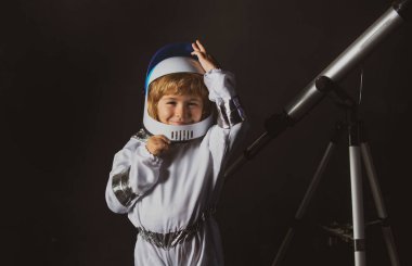 Uzayda sevimli bir astronot çocuk. Çocuk kendini astronot kaskı takmış bir astronot olarak hayal ediyor. Astronot kasklı komik çocuk portresi.