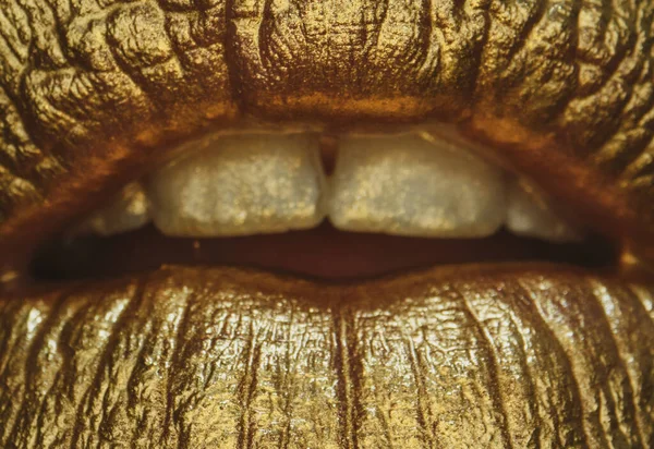 Sexy girl golden lips, gold mouth. Glowing gold skin make-up. Glitter metallic shine golden lipgloss makeup. Golden lips macro close up.