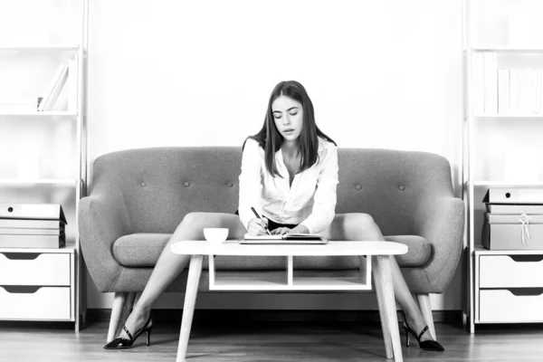 Förförisk sekreterare med sexiga ben sitter på soffan på kontoret. Sexig affärskvinna. Sensuell flicka anställd. — Stockfoto