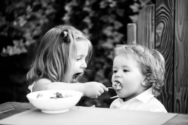Zuster voedt baby jongen. Meisje voedt broer met een lepel. Kindervoeding. — Stockfoto