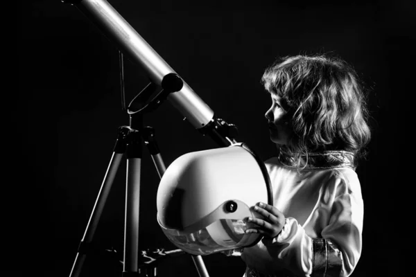 Boy playing to be an astronaut with space helmet and metal suit. Portrait of funny kid with astronaut helmet on black. — Stock Photo, Image