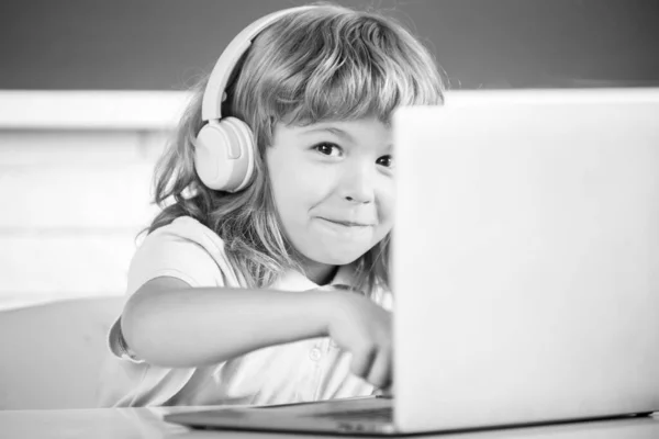 Close-up portret van schattig kind jongen in hoofdtelefoon met behulp van een laptop en online studeren met video call leraar op school. — Stockfoto