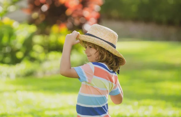 Ritratto di un piccolo ragazzo biondo con cappello di paglia nel parco naturale estivo. Divertente faccia da bambini estivi. Vacanze estive. — Foto Stock