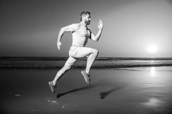Sportieve mannenloper op het zomerstrand. Aantrekkelijke fitte man rennen op zonsondergang licht, workout buiten, joggen met verbazingwekkende zonsondergang op de achtergrond. — Stockfoto