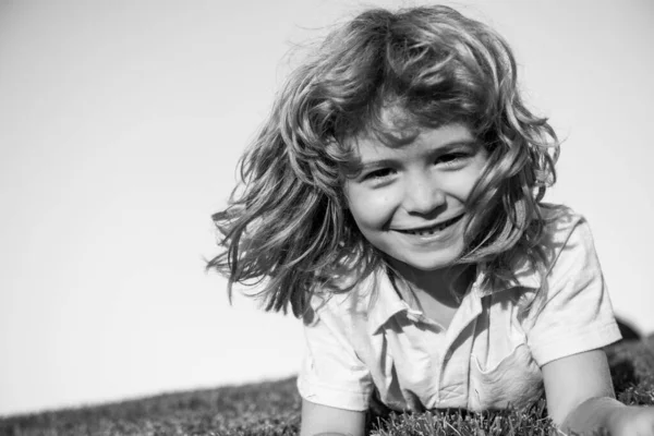 Uśmiechnięty chłopiec cieszący się na trawie i marzący. Dzieci bawią się na letnim boisku. — Zdjęcie stockowe