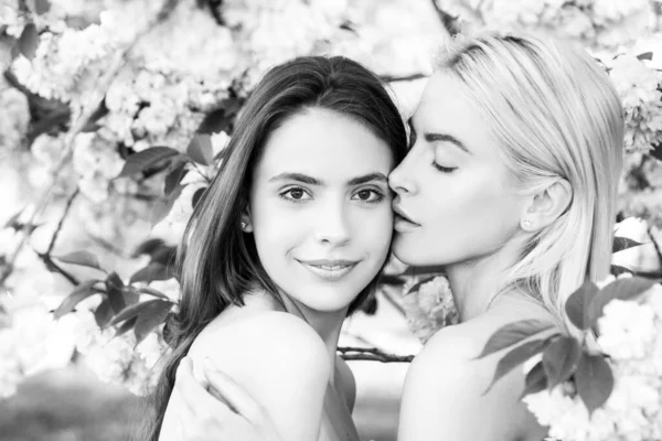 Frühlingsgesicht. Schöne sinnliche sexy Frau in rosa Blumen im Sommerblütenpark. Lesbisches Paar küsst sich. Sinnlicher Kuss, lgbt. Freundinnen weiblich. — Stockfoto
