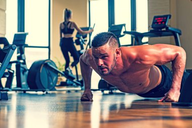 Şınav çeken formda bir adam, şınav çeken bir adam. Gövdesi kaslı, tişörtsüz bir adam spor salonunda..