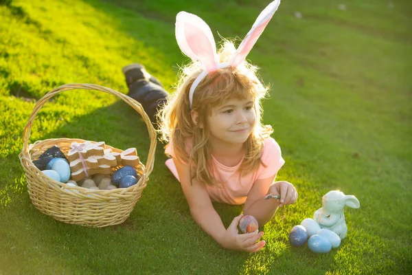 Jongetje met paaseieren en konijnenoren buiten. Grappige jongen, paashaas kinderen. Schattig kind met gelukkig Pasen in park. — Stockfoto