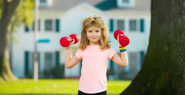 Jongetje aan het trainen met halters op de achtergrond van het park. Kinderen sport outdoor. — Stockfoto