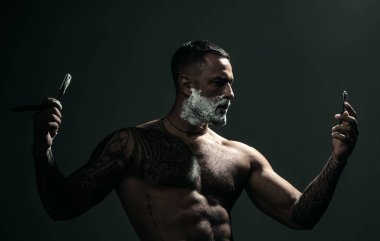 Berber bıçağı. Köpük kremli tıraş fırçası. Klasik jileti olan bir adam. Sakal tıraşı olan seksi bir adam..