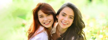 Açık havada kadın kız arkadaşlarla bahar pankartı. Parkta kameraya bakan iki komik arkadaşın portresi. Millet, boş zaman ve eğlence kavramı.