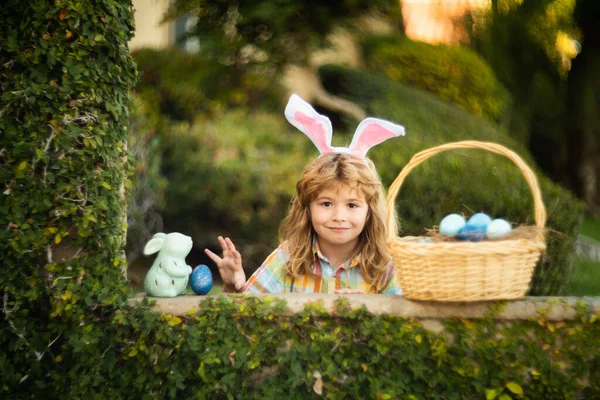 Conejito de Pascua niño cazando huevos con cesta de Pascua al aire libre en feliz día de Pascua. —  Fotos de Stock