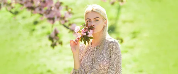 Ritratto all'aperto di giovane bella donna alla moda in posa vicino all'albero di sakura in fiore. Design a molla per banner o intestazione del sito Web, spazio di copia. — Foto Stock