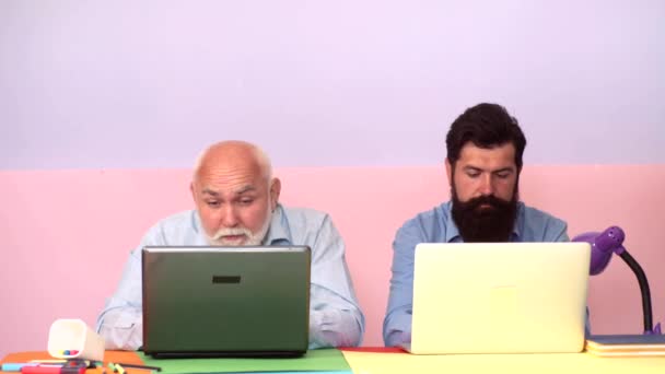 Älterer Sohn mit älterem Vater denkt an ein Online-Projekt mit Laptop am Arbeitsplatz. Ältere Generation. Alt und Jung. — Stockvideo
