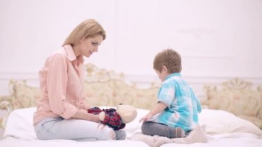 Mutlu bir aile çocuğu ve anne yataktaki yatakta zıplıyor neşeli bir anne yatak odasında sevimli bir çocukla eğlenceli bir oyun oynuyor. Anne ve çocuk yatak odasında konuşuyor..