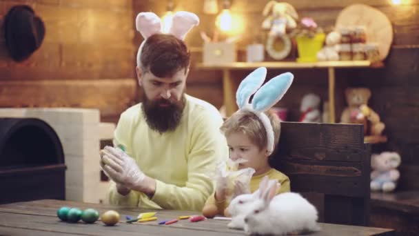 Felice padre e figlio dipinse le uova di Pasqua, indossando orecchie di coniglio il giorno di Pasqua. Vacanze primaverili in famiglia. — Video Stock