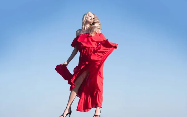 Vrouw in rode jurk beweging aan de hemel. Fashion outdoor foto van prachtige sensuele vrouw in elegante kleding. Schoonheid en mode meisje. Zorgeloze vrouwen buiten. — Stockfoto