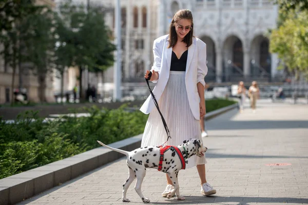 Открытый портрет молодой элегантной женщины, идущей по улице. Молодая модель прогулки с собакой, городской стиль. — стоковое фото