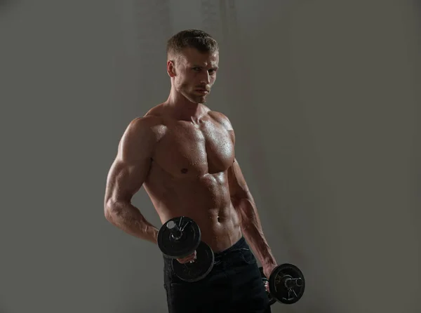 Sportieve romp, man met halters. Portret van jonge atleet die oefeningen doet met halter in geïsoleerde donkere studio. Crossfit, sport en een gezonde levensstijl. — Stockfoto