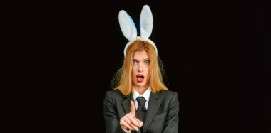 Tavşanlı Paskalya bayrağı. Güzel tavşan kız göz kırpıyor ve dili çıkıyor. Göz kırpan tavşan kız suratına yakın çekim. Siyah Paskalya Tavşanı takan seksi kadın..