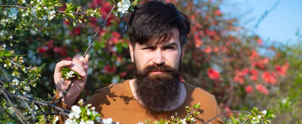 Bannière de printemps de l'homme en plein air. Portrait d'un bel homme sur fond de printemps fleuri. — Photo