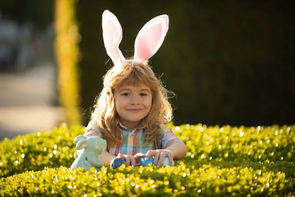 Fijne paasdag. Kind met konijnenoren. Kinderen jagen op paaseieren in het park. Close-up portret van leuke kinderen. — Stockfoto